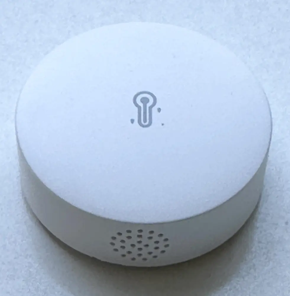 Runder, weißer Sonoff SNZB-02P Zigbee-Temperatur- und Luftfeuchtigkeitssensor mit Thermometer-Symbol auf der Oberseite und seitlichen Lüftungsöffnungen.